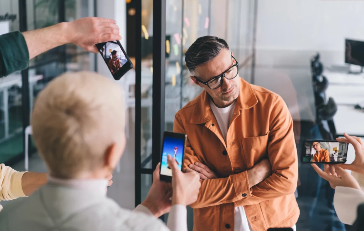 shutterstock_2287857953 1 | TVGURU.cz Muže fotí tři lidé na telefon.