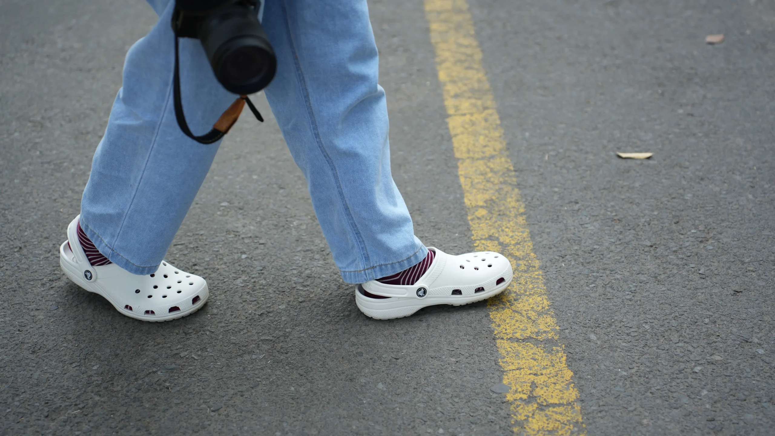 shutterstock_2662119223-2 | TVGURU.cz Člověk má na sobě bílé boty crocs a přechází silnici.