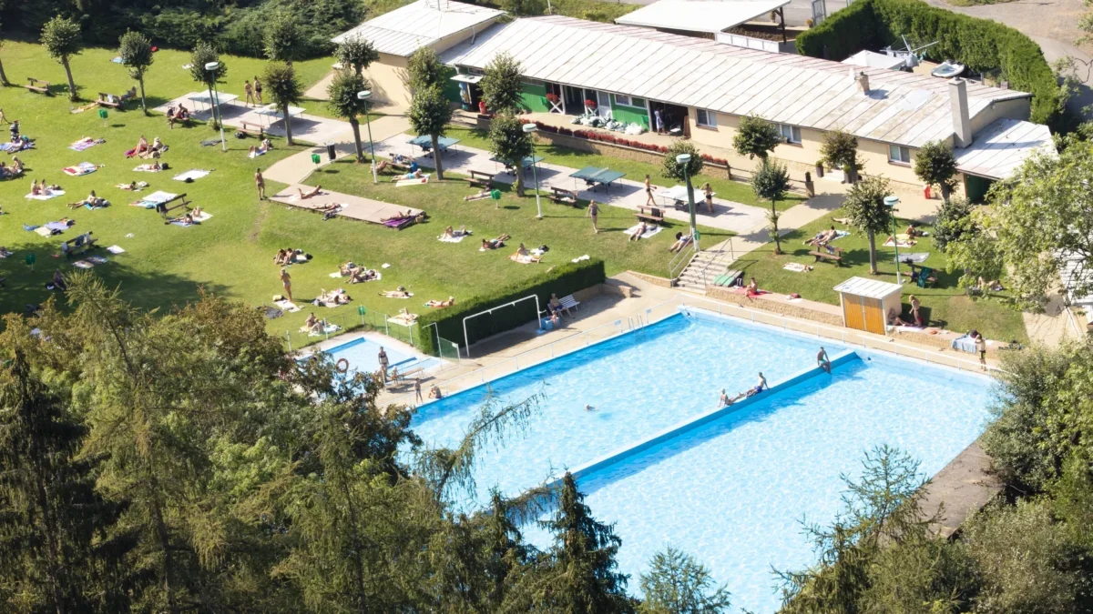 Koupaliště skládající se z bazénu a travnatí plochy.