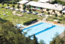 Koupaliště skládající se z bazénu a travnatí plochy.