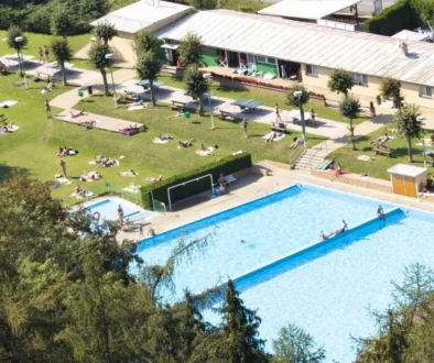 Koupaliště skládající se z bazénu a travnatí plochy.