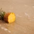 Pineapple half with green crown resting on a wooden table surface.