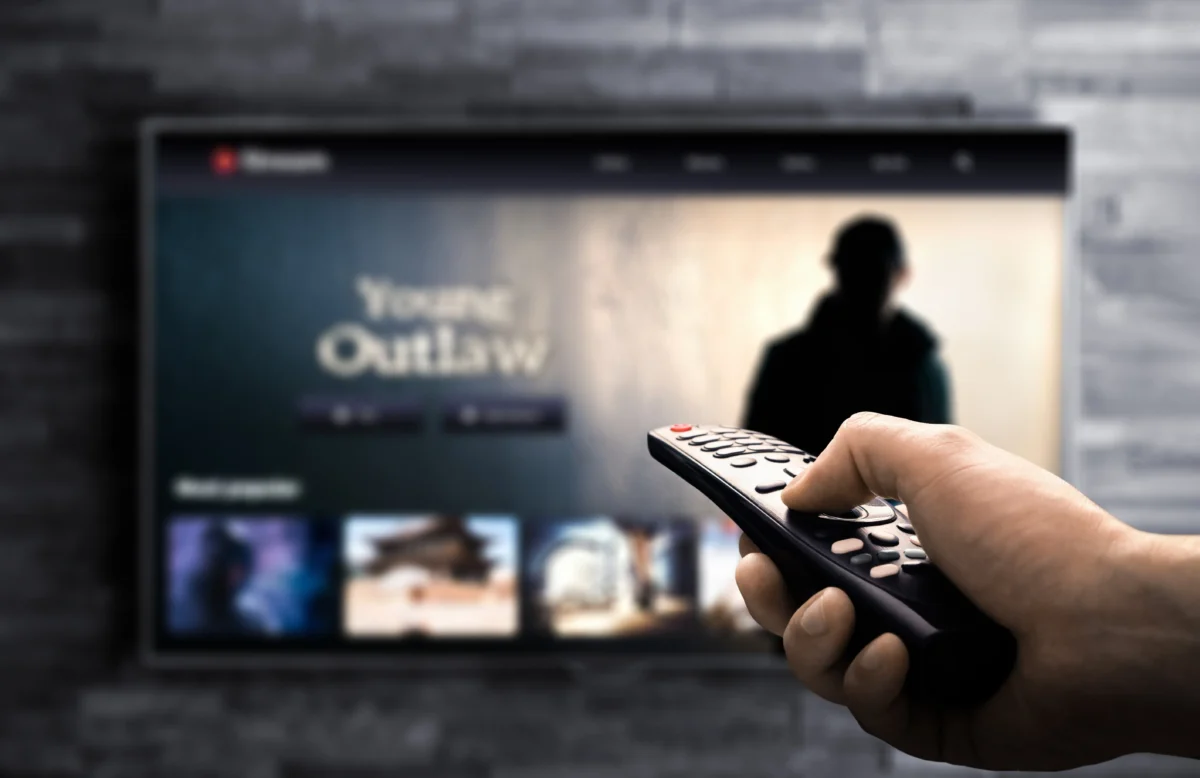 Ruka s ovladačem namířeným na televizi