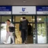 Two people exit a Czech public service office under blue signage that says Úřad práce ČR above glass doors.