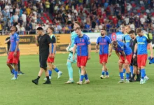Fotbalisté jdou po hřišti.