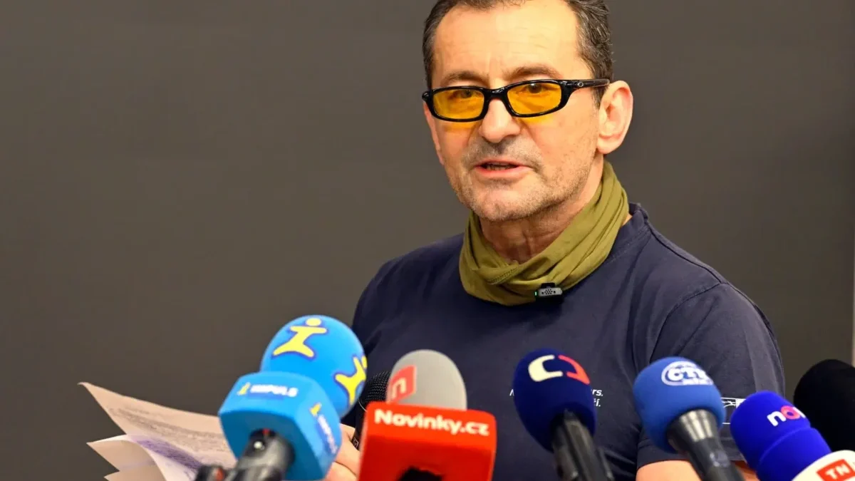 muž v brýlích s mikrofony před sebou