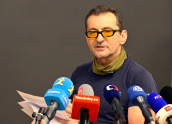 muž v brýlích s mikrofony před sebou
