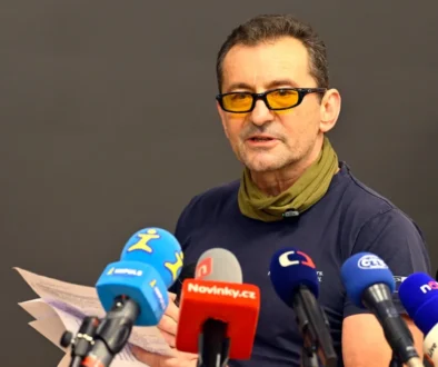 muž v brýlích s mikrofony před sebou