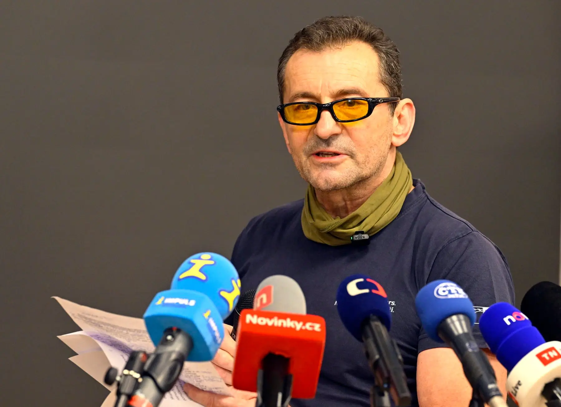 muž v brýlích s mikrofony před sebou
