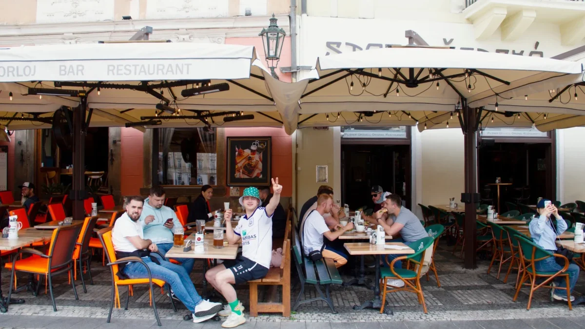 Lidé sedí na zahrádce restaurace.