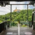 View from a tram platform toward a yellow hilltop building surrounded by green trees, with metal framework and rails in the foreground.