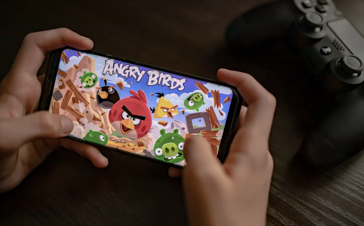 Člověk na mobilu hraje hru Angry Birds.
