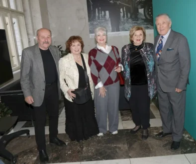 Five seniors pose together for a group photo in a marble-floored indoor venue, smiling at the camera.