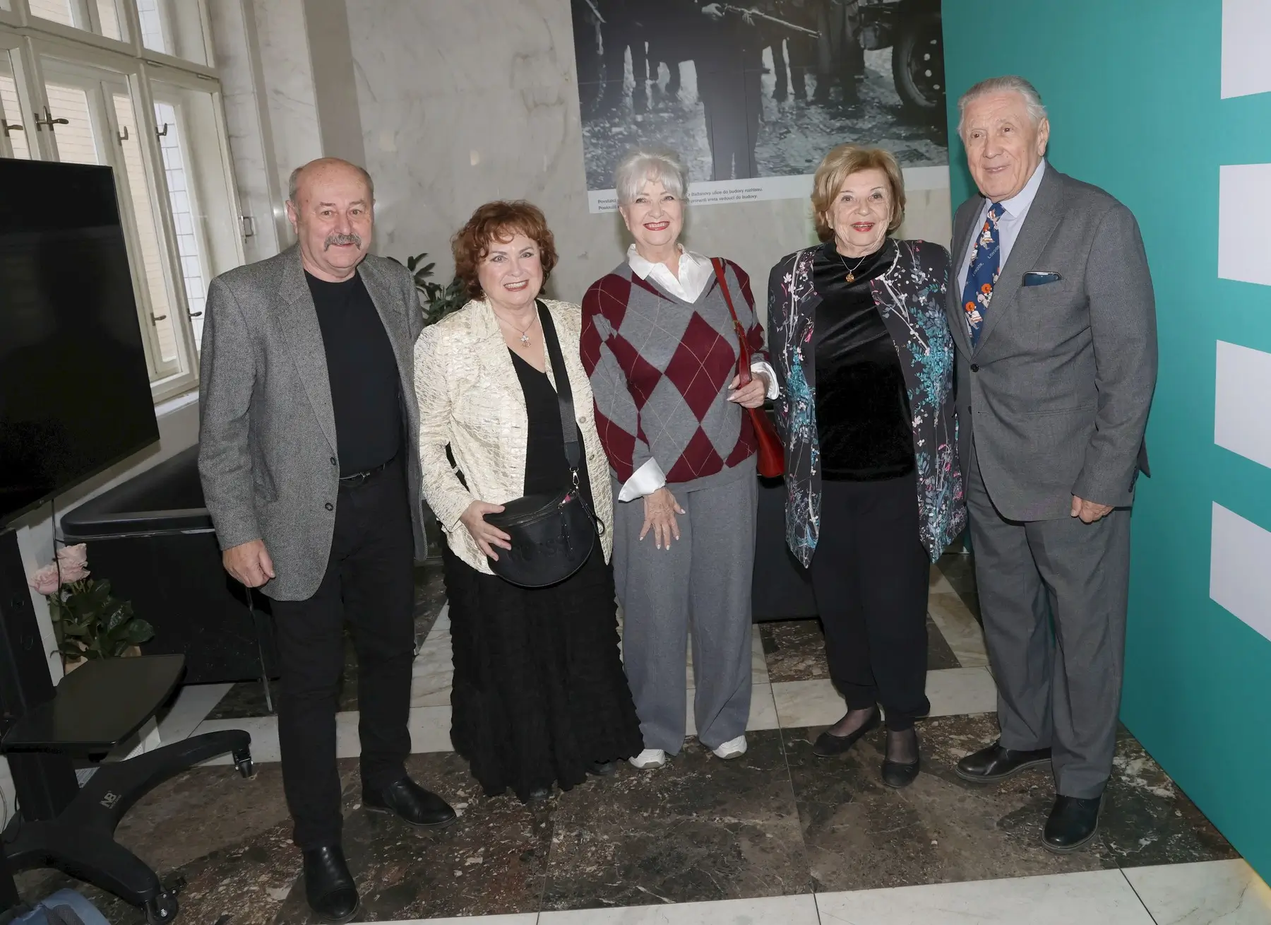 Five seniors pose together for a group photo in a marble-floored indoor venue, smiling at the camera.