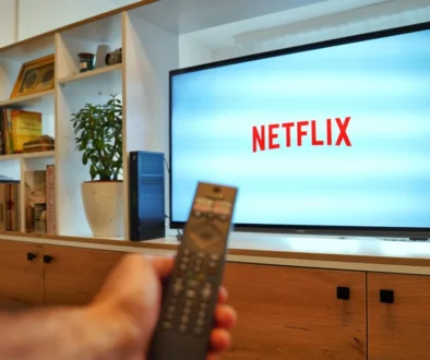 Person holding a remote in front of a TV displaying the Netflix logo in a living room setting