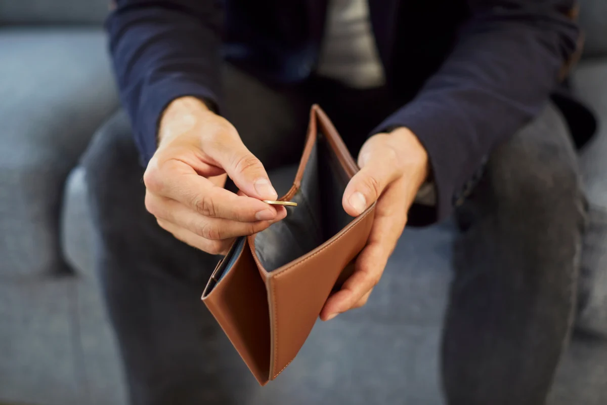 Peníze nejsou vždy zárukou štěstí. Zdroj: Shutterstock | TVGURU.cz Ruka vyndavající minci z peněženky