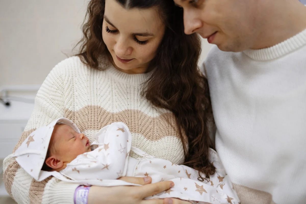 Aktuálně jsou populární i modernější varianty. Zdroj: Shutterstock | TVGURU.cz Žena chovající miminko s partnerem
