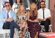 Jennifer Aniston sedí mezi lidmi.