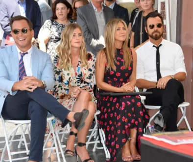 Jennifer Aniston sedí mezi lidmi.