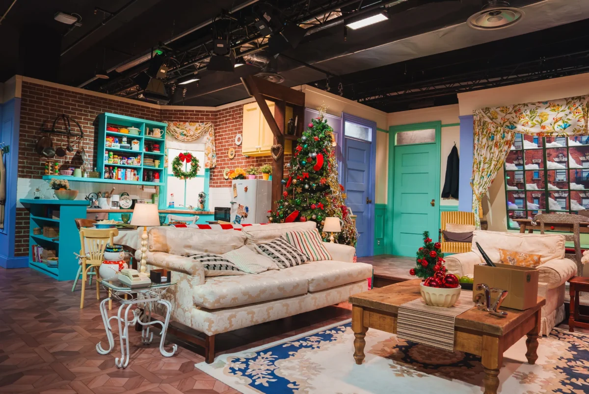 Colorful holiday stage living room with a Christmas tree, brick wall, turquoise shelves, and teal doors in a cozy set.