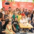 Group of people posing for a celebratory photo around a table with a two-tier cake, in front of a red ULICE backdrop.