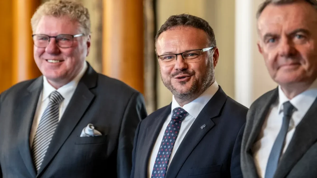 René Zavoral stojí mezi dvěma muži.