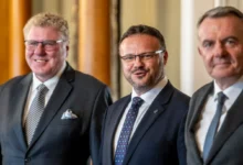 René Zavoral stojí mezi dvěma muži.