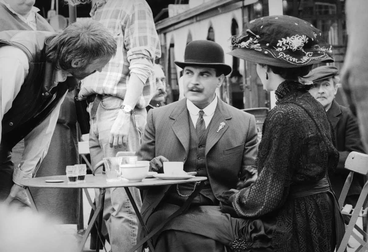Hercule Poirot opět přichází na scénu. Zdroj: Shutterstock | TVGURU.cz Černobílá fotografie muže a ženy sedících u stolu