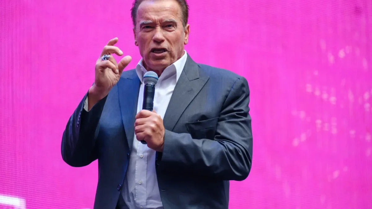Arnold Schwarzenegger drží mikrofon.