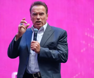 Arnold Schwarzenegger drží mikrofon.