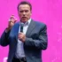Arnold Schwarzenegger drží mikrofon.