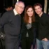 Three people pose for a photo together: an older man on the left, a woman in the middle, and a younger man on the right, smiling at the camera.
