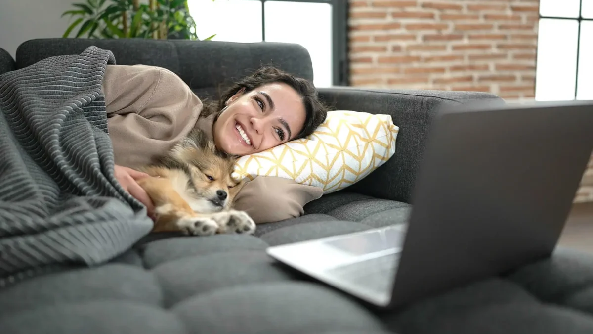 shutterstock_2380584655 1 | TVGURU.cz žena leží na gauči se psem a kouká na film na notebooku
