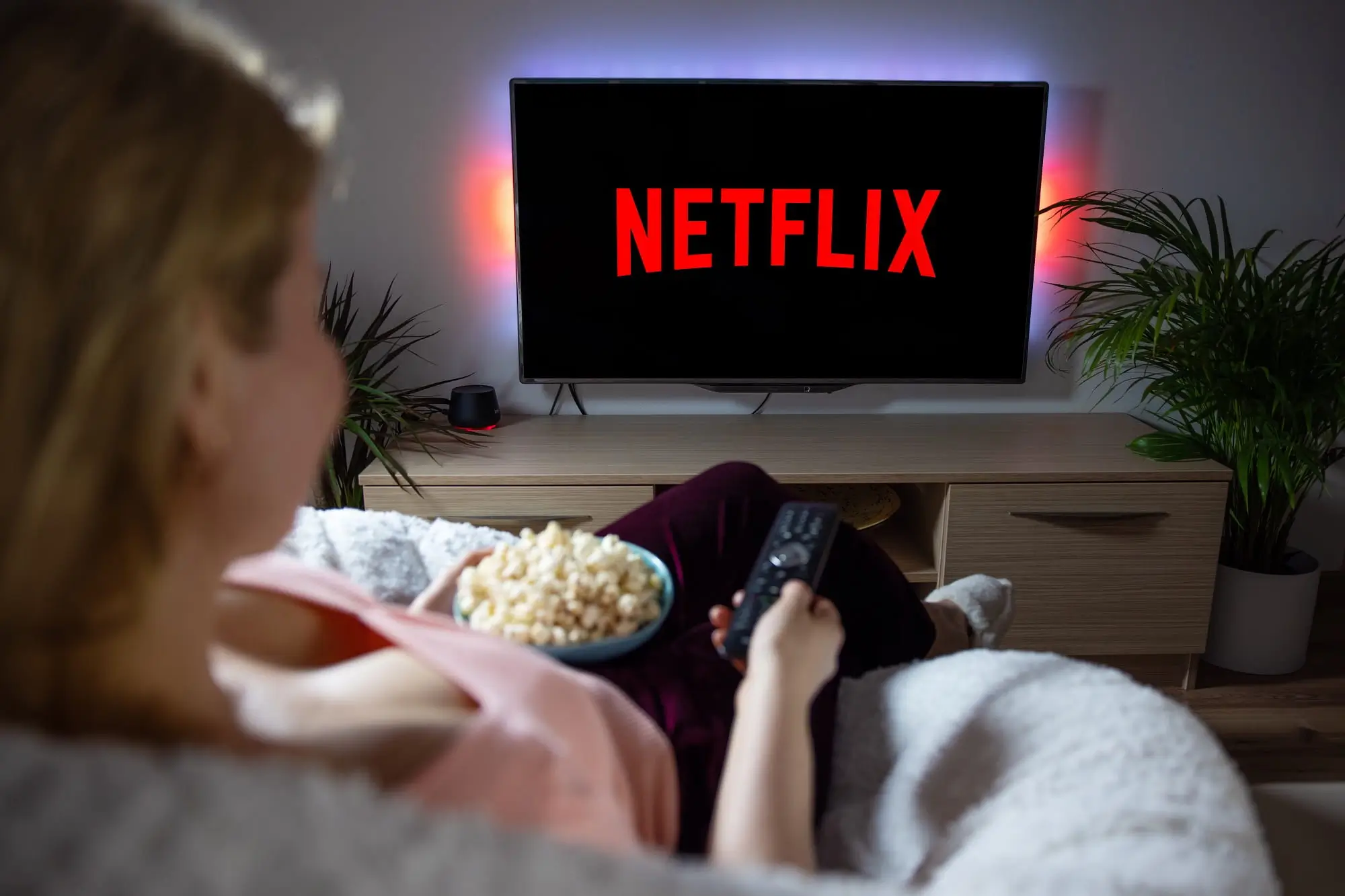 paní s popcornem sedí na gauči a kouká na netflix