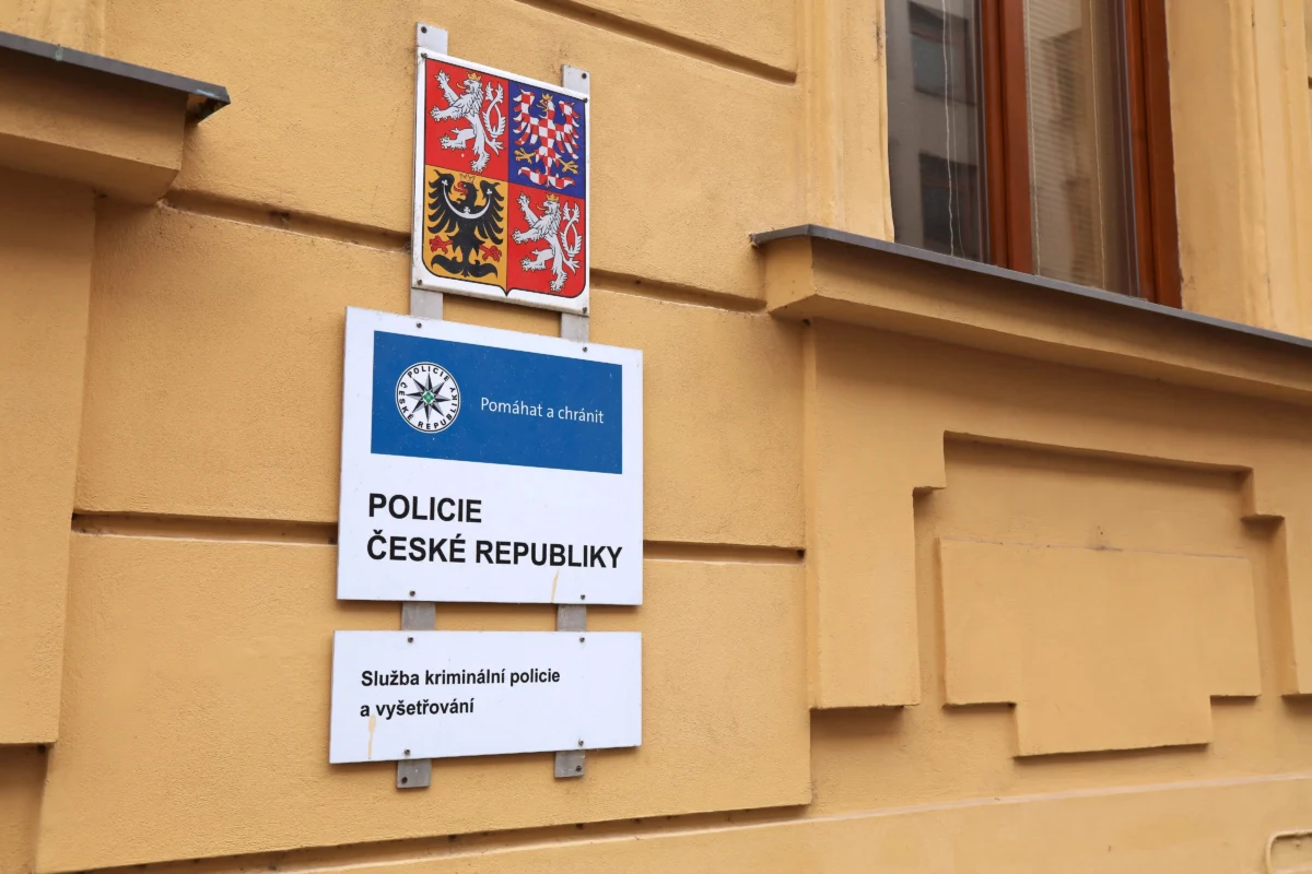 shutterstock_2525924207 1 | TVGURU.cz Yellow wall with police signage: a blue sign reading "POLICIE ČESKÉ REPUBLIKY" and an inset shield with the Czech coat of arms above it.