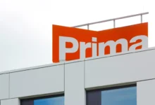 Modern building facade with an orange sign showing large white letters (brand name partially visible).