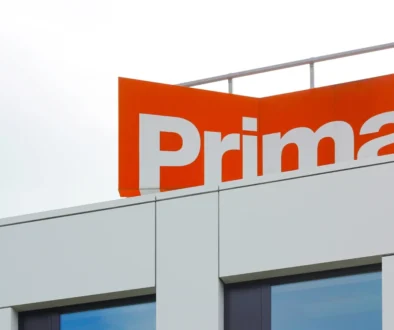Modern building facade with an orange sign showing large white letters (brand name partially visible).