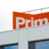 Modern building facade with an orange sign showing large white letters (brand name partially visible).