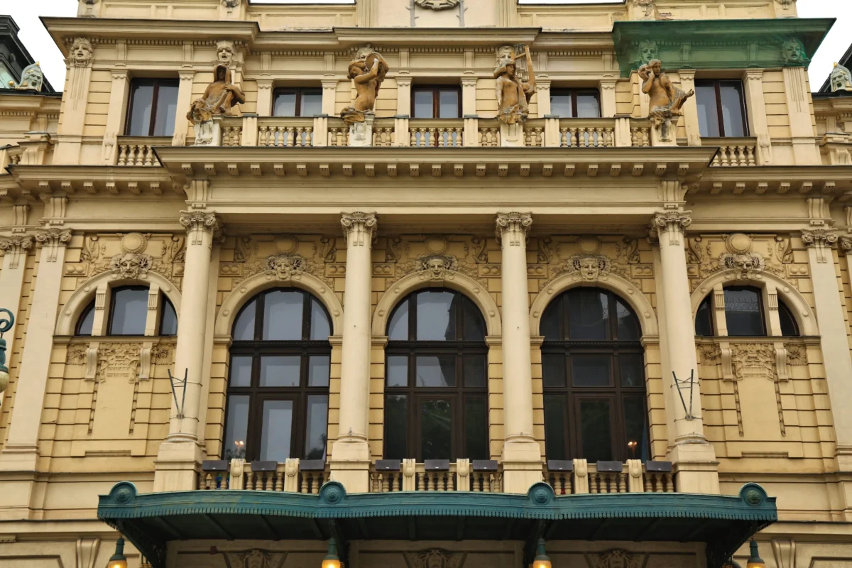 Historic beige building façade with statues along a balcony and ornate columns