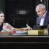 Prostředí televizní talk show s usmívající se hostující ženou a moderátorem u stolu, na stole viditelný chléb, pečivo a nápoje. V popředí s Janem Krausem