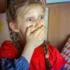 A young girl with braided hair and a red shirt covering her mouth with her hands, her eyes wide in surprise.