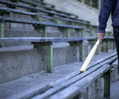 Muž jde podél laviček s baseballovou pálkou.