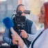 Muž stojí za kamerou a natáčí reportáž.