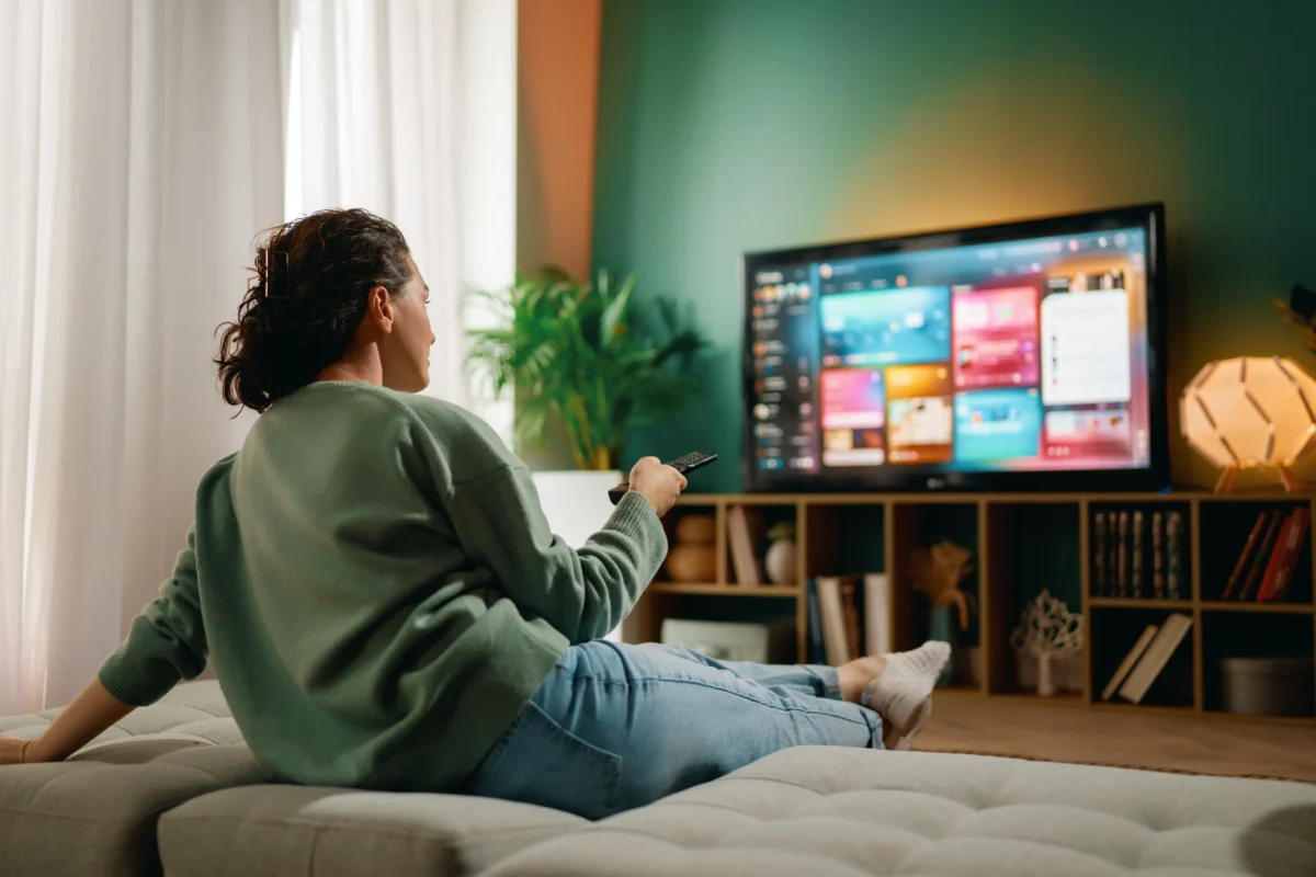 Žena sedí na gauči a kouká na tv