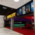 Cinema lobby with a bright yellow 'CINEMA CITY' sign and film posters along a black wall.