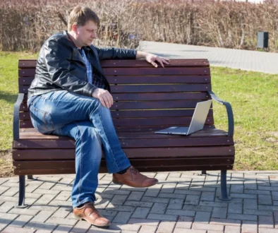 Muž sedí s notebookem na lavičce.