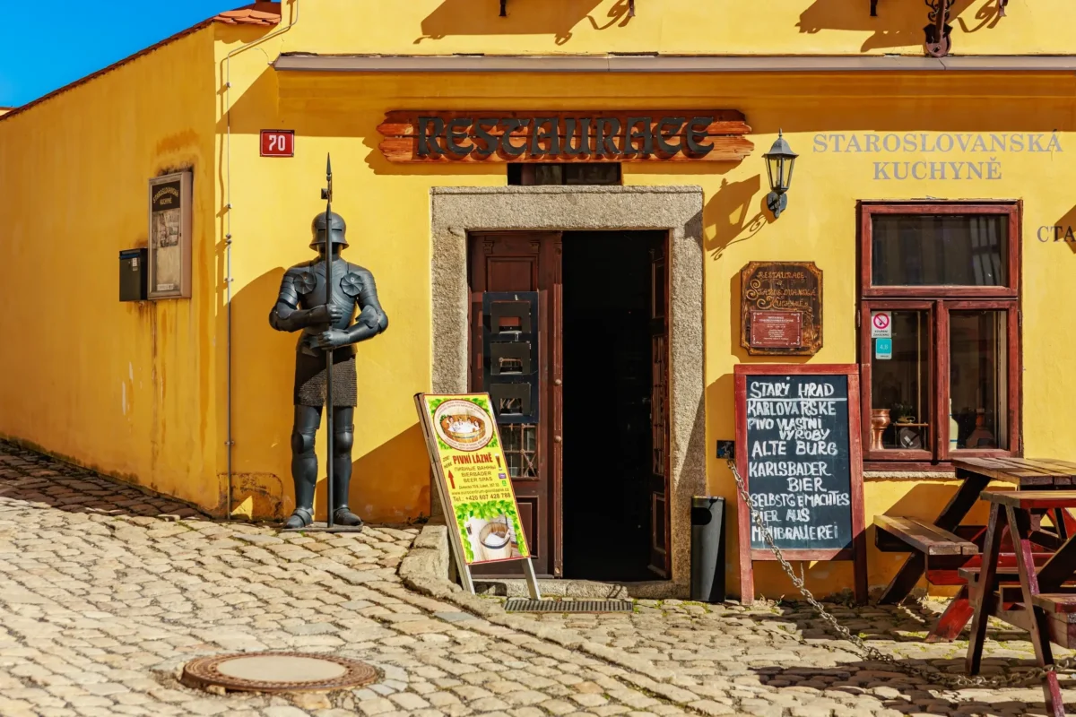 Žlutá budova restaurace s venkovním posezením