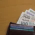 Z peněženky čouhají bankovky.