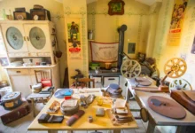 Cluttered vintage workshop with film reels, projectors, and wooden cabinets against yellow walls with retro posters and green trim patterns.