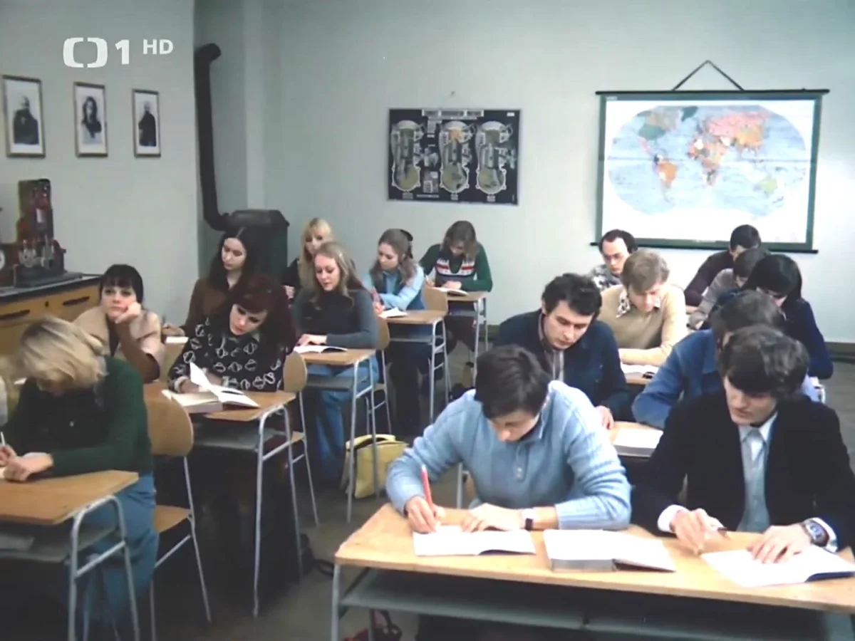 Ve třídě se dnes už nenachází krbová kamna. Zdroj: Filmovamista.cz | TVGURU.cz Třída se studenty, kteří píšou do sešitu.